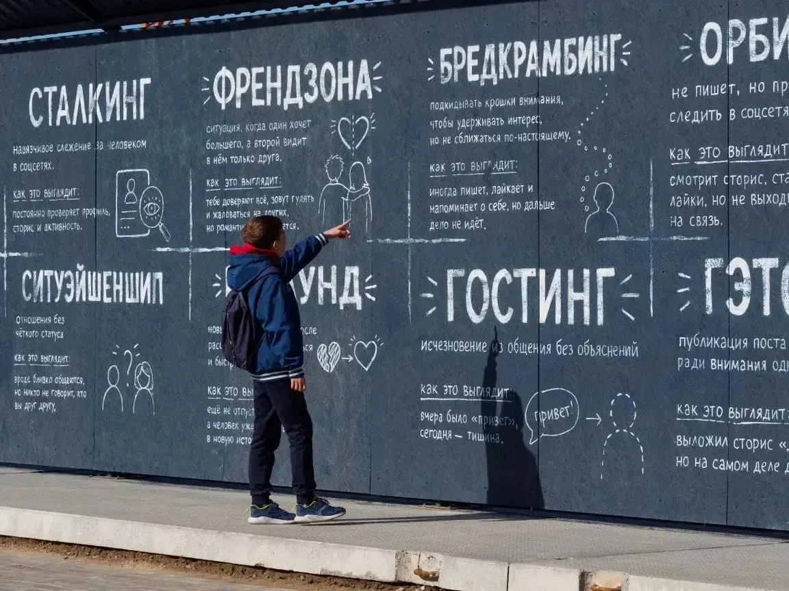 Ограждение строящейся школы на Левом берегу разрисовали пояснениями к эмодзи, сленгу и бытовым метафорам — авторы предлагают взрослым и молодёжи лучше понимать друг друга.
