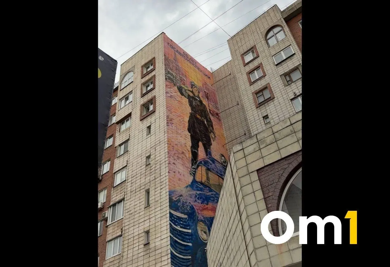 На фасаде дома на улице Масленникова появился мурал, посвящённый 90‑летию Госавтоинспекции. Образ героини основан на картине Василия Волкова — посвящение первой женщине‑регулировщице Омской области Любови Степановне Низовцевой.