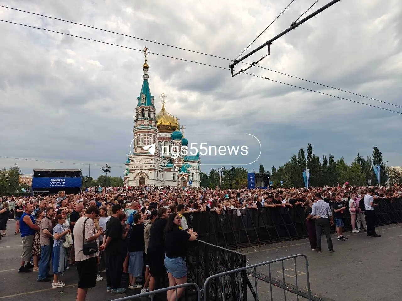 Жители Омска подтягиваются к площадке: диджей разогревает публику, появляются первые плакаты — концерт начнётся в ближайшие минуты.
